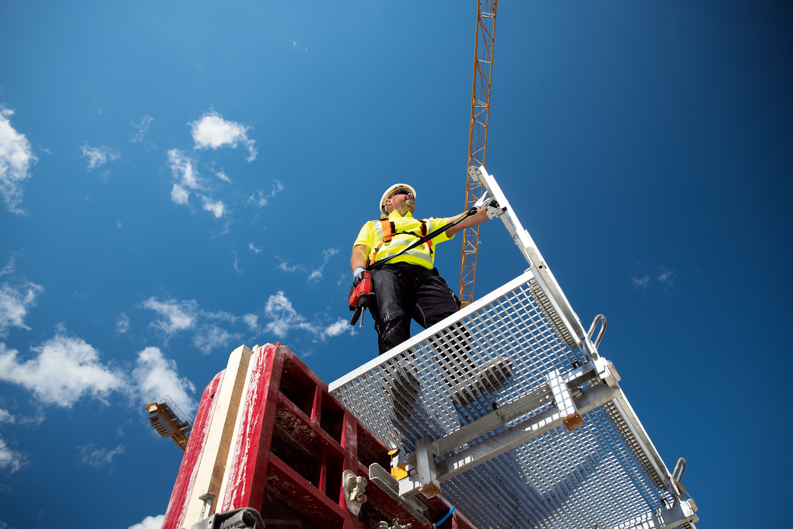 Pracovník stojí na plošině se strojem připevněným bezpečnostním popruhem
