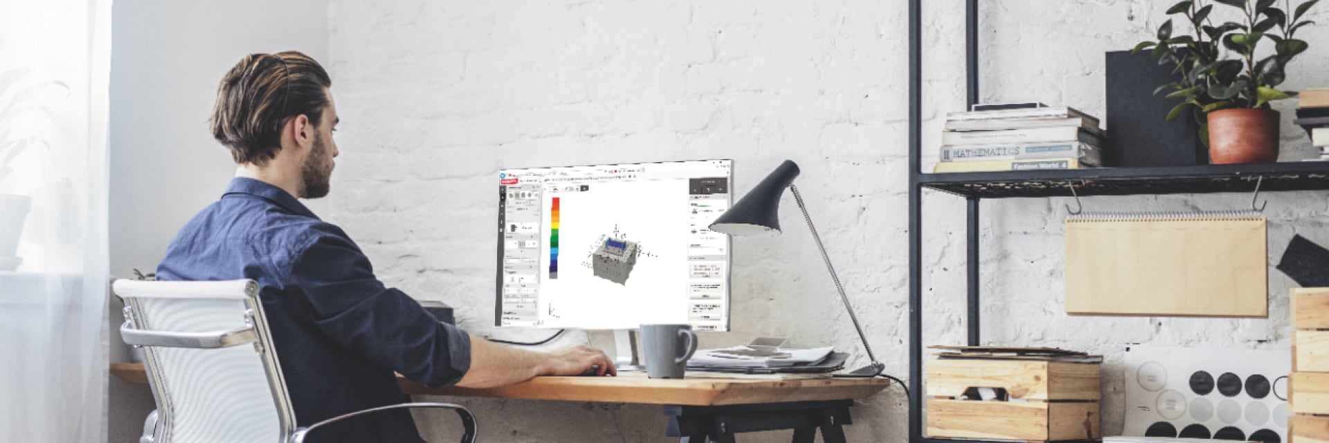 Man sitting at desk looking at anchor design software screen on desktop